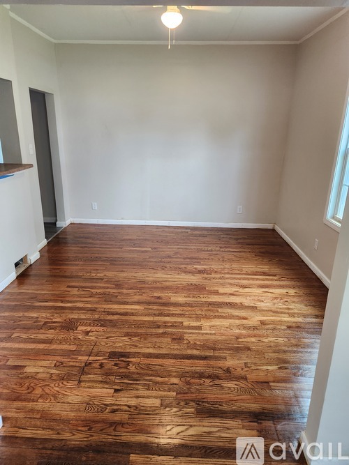 A room with wooden flooring and white walls.