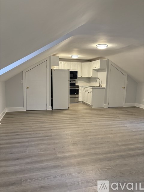 A kitchen area with white cabinets and a wooden floor.