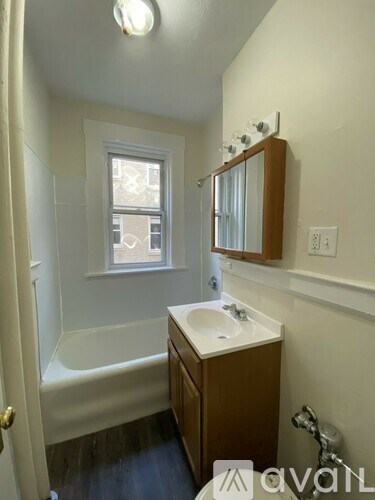 A small bathroom with a tub, sink and mirror.
