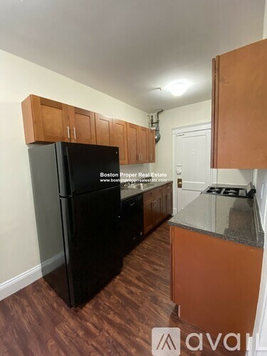 A kitchen with a black fridge and wooden cabinets.