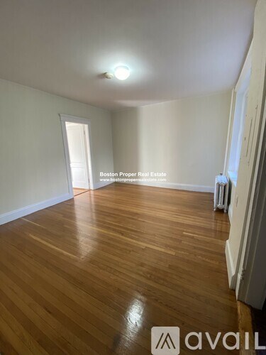 A room with wooden flooring and a window with a sign that says Boston Proper Real Estate.