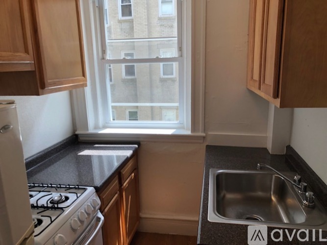 A kitchen with a stove, sink, and window.