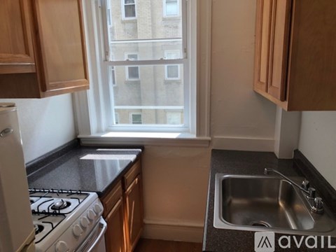 A kitchen with a stove, sink, and window.
