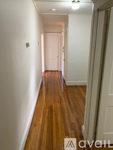 A long hallway with wood floors and white walls.