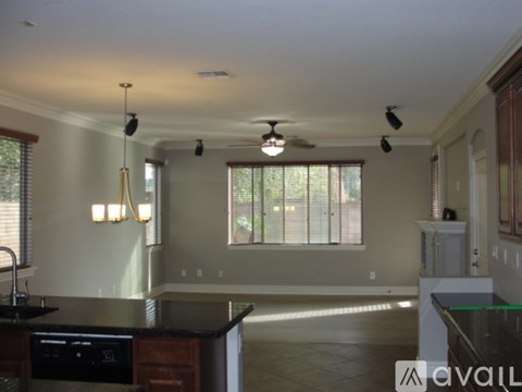 A kitchen with a black counter top and a ceiling fan.
