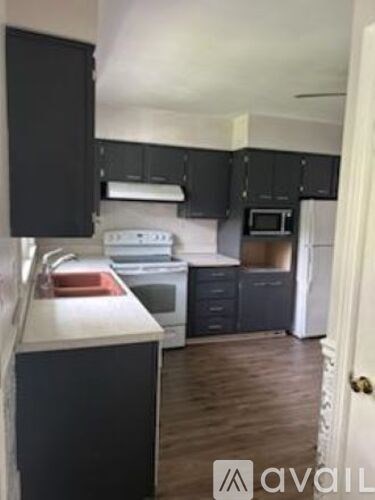 A kitchen with black cabinets and white appliances.