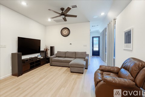 A living room with a brown leather couch and a flat screen TV.