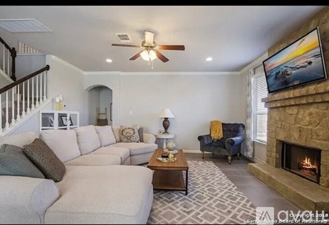 A living room with a fireplace and a television on the wall.