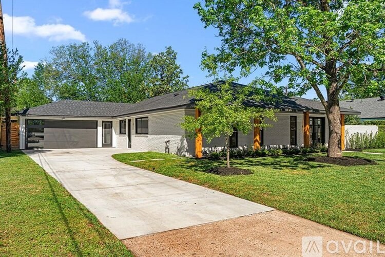 A house with a driveway and a tree in front.