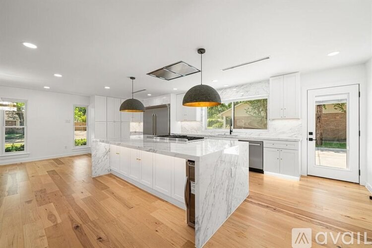 A modern kitchen with white cabinets and a marble island.