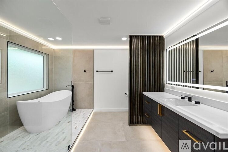 A modern bathroom with a white freestanding bathtub and a large mirror.
