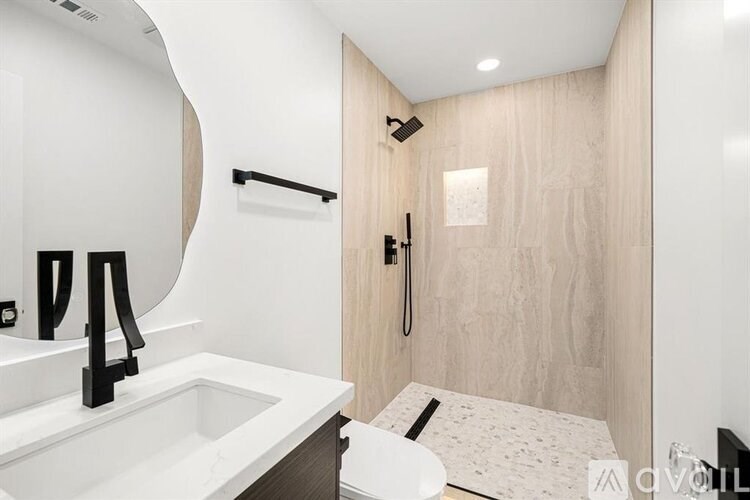 A modern bathroom with a sink, mirror, and shower.