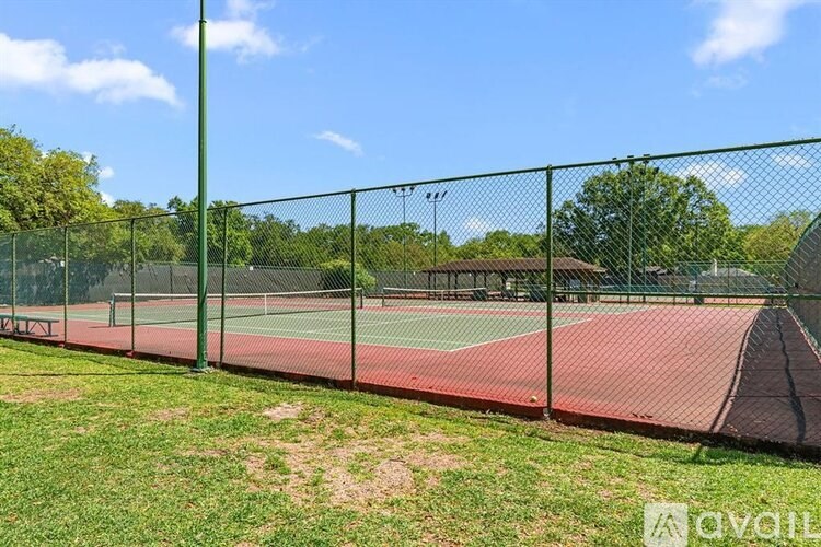 A tennis court is enclosed by a green fence.