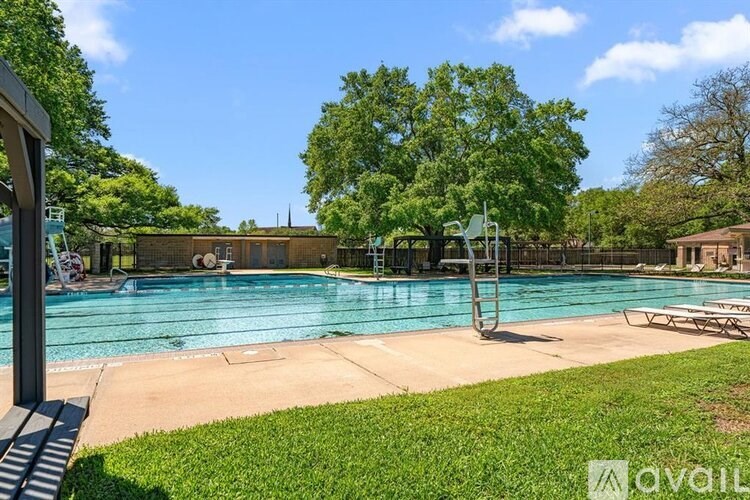 A large outdoor swimming pool surrounded by trees and a grassy area.