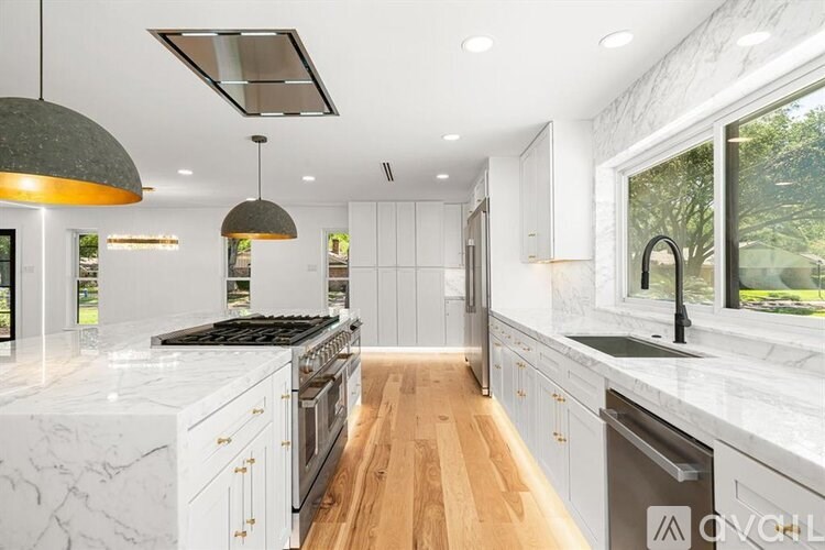 A modern kitchen with white marble countertops and wooden floors.