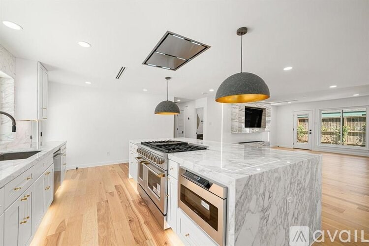 A modern kitchen with a marble island and stainless steel appliances.