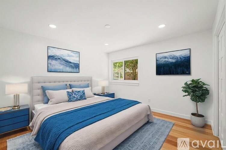 A bedroom with a large bed and two pictures on the wall.