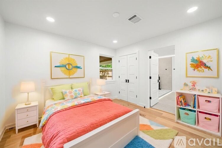 A bedroom with a red bedspread and a white bed.