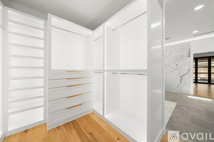 A white interior space with wooden floors and a marble wall.