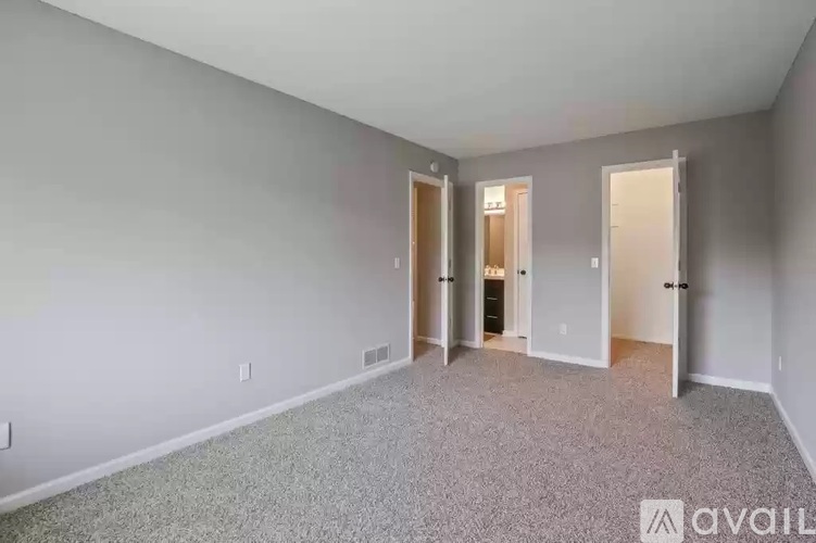 A spacious room with carpeted floor and three doors.
