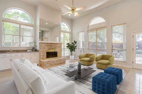 A living room with a white couch, a stone fireplace, and a ceiling fan.