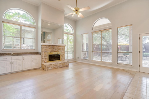 A spacious living room with a stone fireplace and hardwood floors.