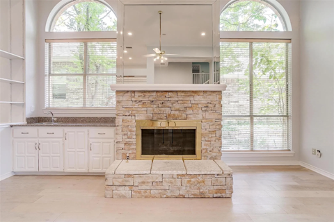 A stone fireplace in a room with a large window.