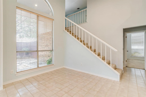 A spacious room with a staircase and tiled flooring.