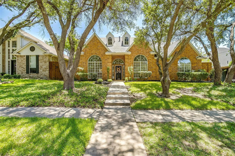 A large house with a brick facade and a long driveway.