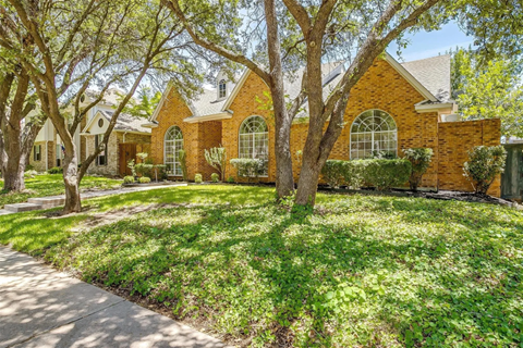 A house with a red brick exterior and a green lawn.