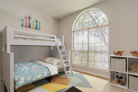 A white bunk bed with a ladder is in a room with a window.