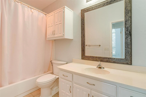 A white bathroom with a toilet, sink, and shower curtain.
