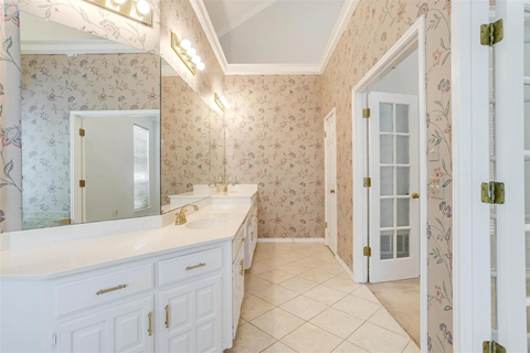 A bathroom with a floral wallpaper and a white vanity.