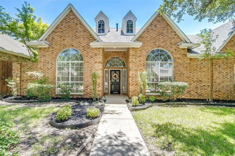 A brick house with a black door and windows.