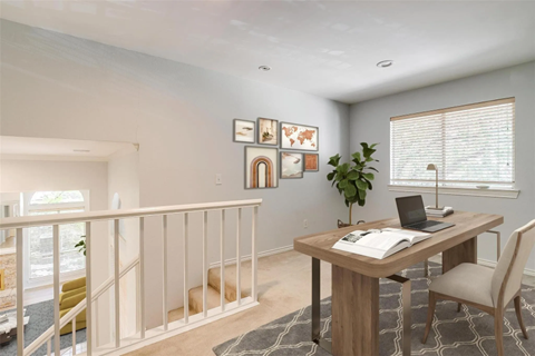 A room with a desk, chair, and pictures on the wall.