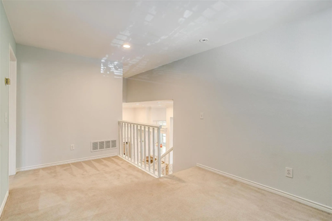 A spacious room with a white ceiling and a carpeted floor.
