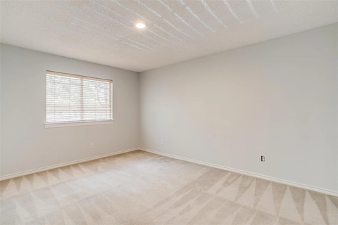 A room with a window and a carpeted floor.