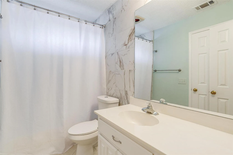 A white bathroom with a marble wallpaper.