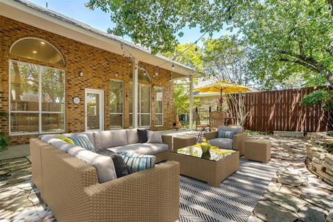 A patio with a couch, chairs, and a table with a yellow umbrella.