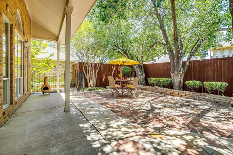 A patio with a table and chairs under a yellow umbrella.