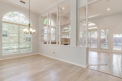 A spacious room with a large window and a chandelier hanging from the ceiling.