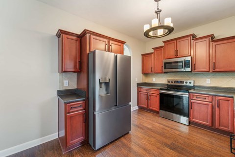 A kitchen with wooden cabinets and a stainless steel refrigerator.