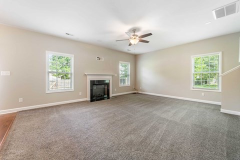 A spacious living room with a fireplace and a ceiling fan.