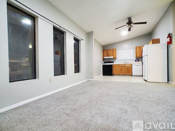A spacious room with a ceiling fan and a kitchenette.