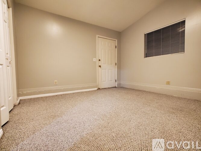 A room with a door and a window with blinds.