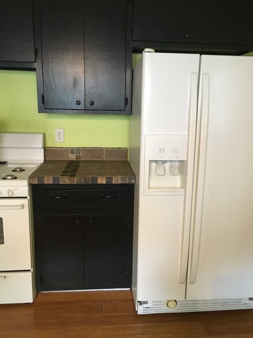 A white refrigerator stands next to a white stove in a kitchen.
