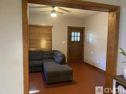 A living room with a grey couch and a wooden door.