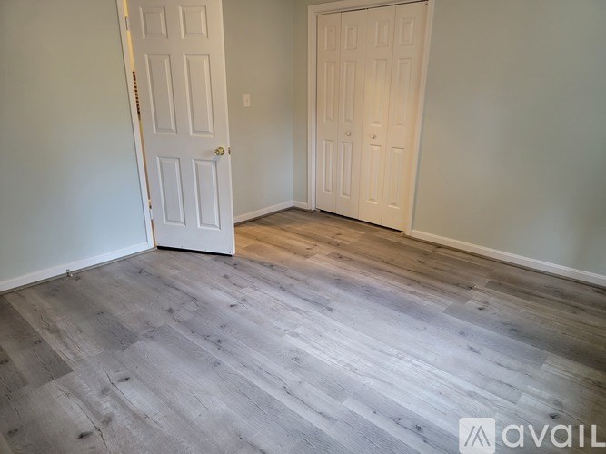 A room with two white doors and wooden flooring.
