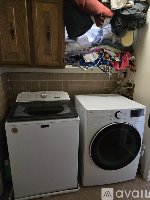 Two front loading washing machines are in a small laundry room.