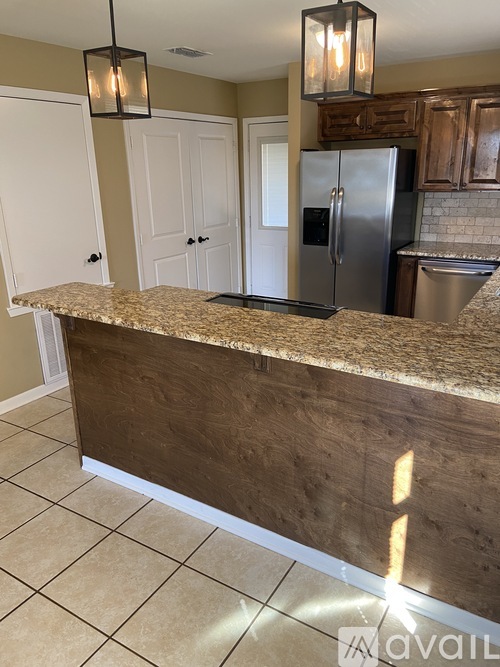 A kitchen with a granite countertop and a stainless steel refrigerator.